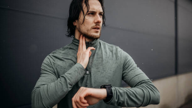 Na slici je čovek koji trenira i istovremeno proverava svoj puls.