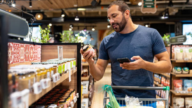 Na slici je prikazan čovek u marketu, koji razmišlja šta jesti posle treninga.