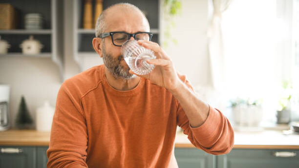 Na slici je prikazan čovek koji pije vodu iz čaše.