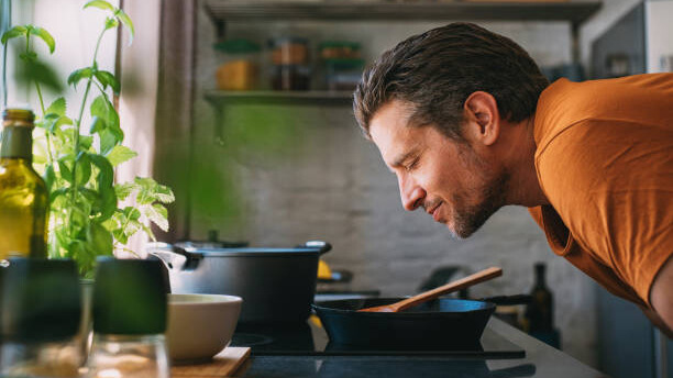 Na slici je prikazan čovek koji uživa u spremanju i degustaciji hrane.