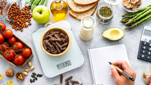 Na slici je prikazan širok izbor namirnica i vaga za merenje pri pravljenju jednog obroka.