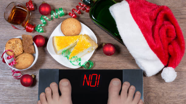 Na slici je šaljivi prikaz vage koja odbija da pokaže broj kilograma, a vidimo da su uzrok tome slatkiši i loše životne navike.