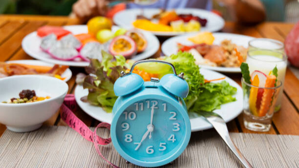 Na slici je prikazan sat ispred tanjira sa raznim jelima - odnosi se na to koliko je važan raspored unosa određenih namirnica.
