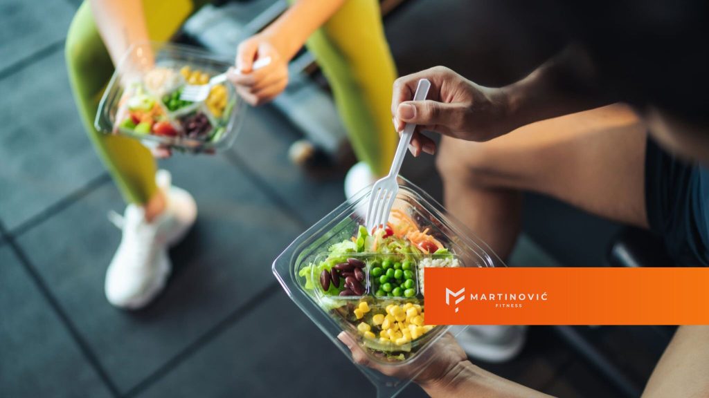 Na slici je prkazan par u teretani, sa svojim obrocima i idejom šta jesti posle treninga.