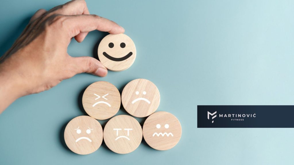 Na slici je prikazana ruka koja redja emotikone i stavlja smajli na vrh - kao podsetnik da trebamo smanjiti kortizol i nastojiti da popravimo raspoloženje.