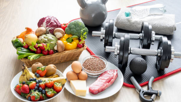 Na slici su prikazane hranjive namirnice i oprema za trening snage. Na temu: Kako muškarci da skinu sale i jedu slatkiše - odgovor je pravilnom kombinacijom ishrane i treninga snage.