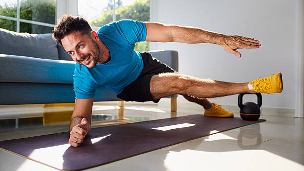 Na slici je prikazan čovek koji vežba kod kuće uz minimalnu opremu i postiže odlične rezultate.