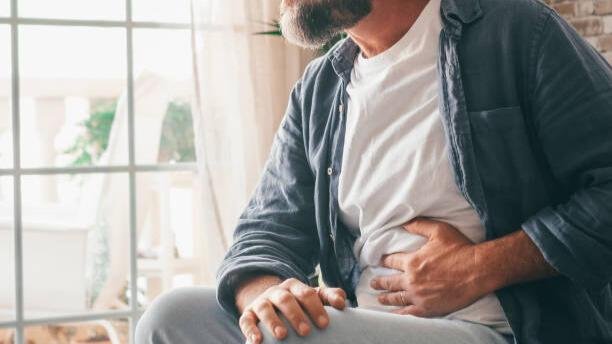 Na slici je muškarac srednjih godina koji se drži za stomak.