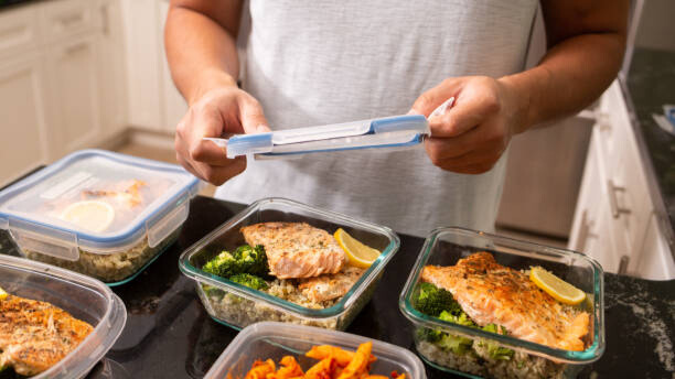 Na slici je prikazan čovek koji sortira hranu po kutijama za obrok.