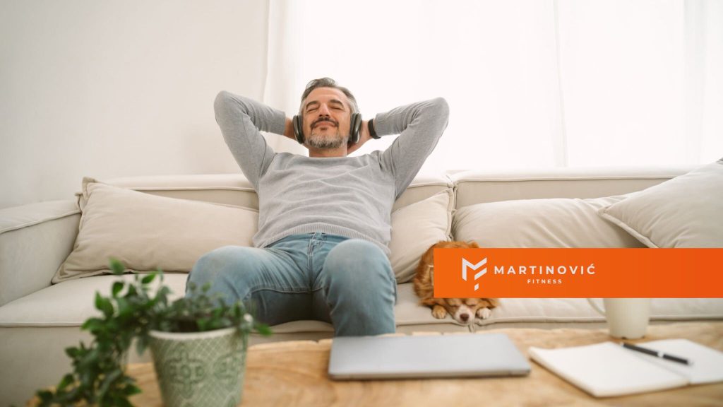 Na slici je čovek koji odmara na kauču, slušajući muziku.