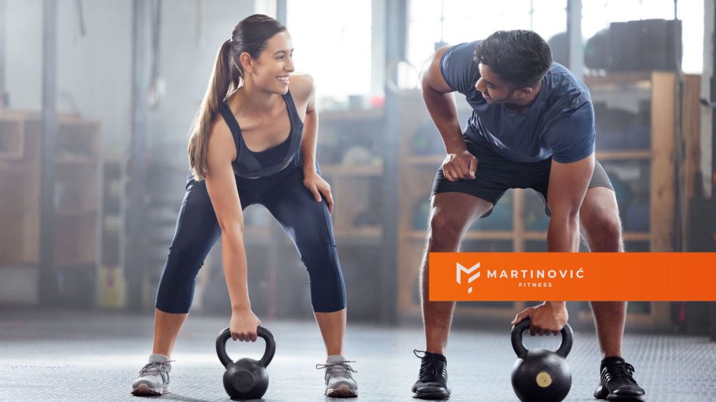 Na slici je prikazan par koji trenira u teretani sa bučicama, kao naslovnica bloga na temu: 6 stvari za kvalitetan trening.