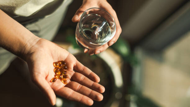 Na slici je čovek koji konzumira suplemente kao dodatak ishrani.