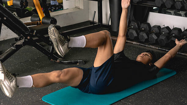 Na slici je muškarac koji radi dead bug vežbu.