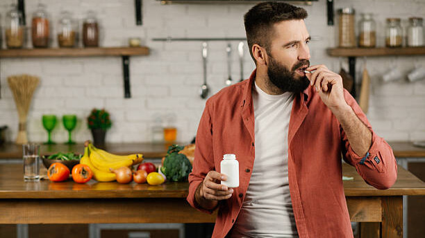 Na slici je muškarac koji konzumira suplemente: Vitamin D i Magnezijum.